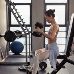 photo of woman sitting while holding dumbbells